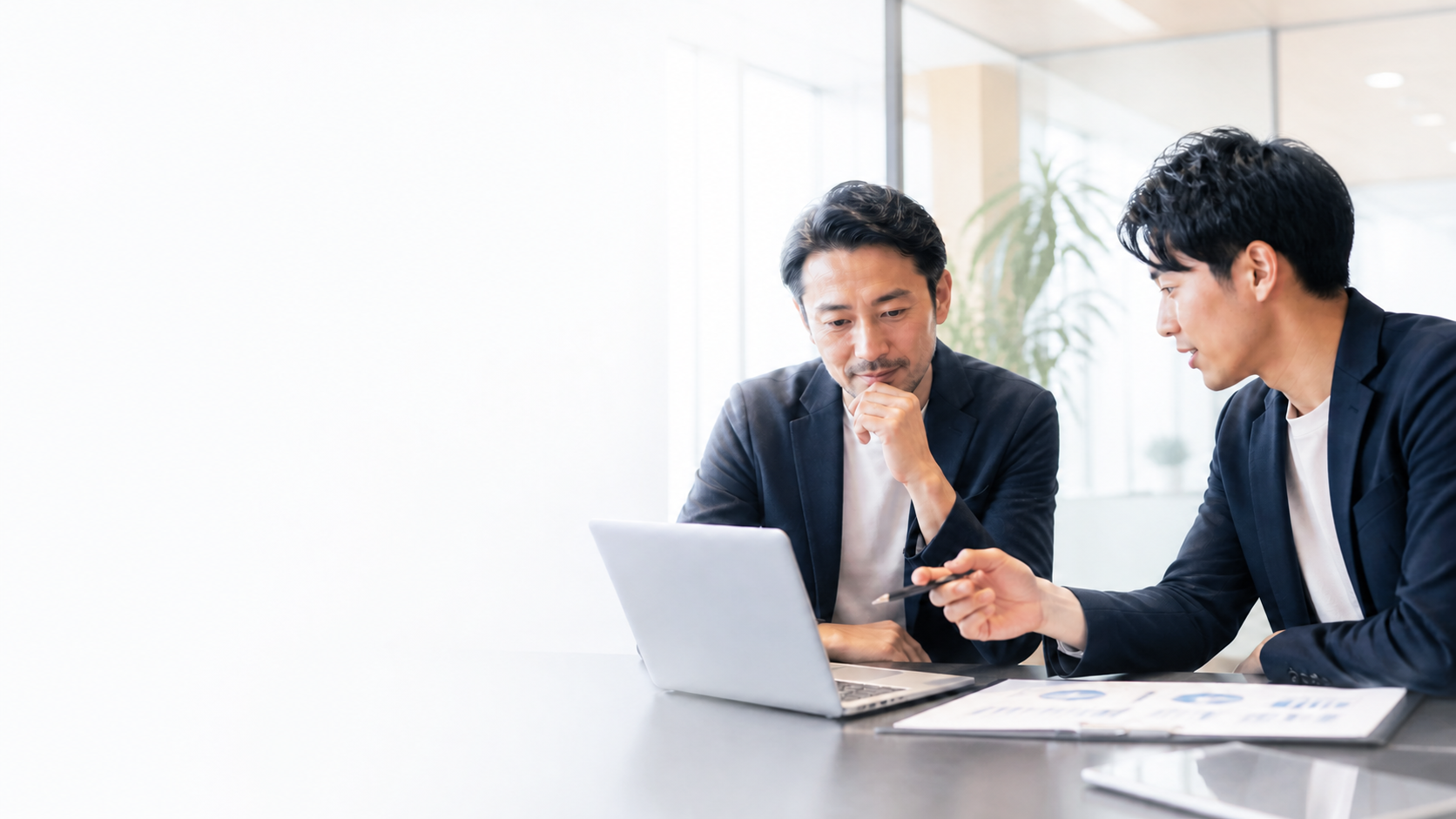 ノートパソコンを見ながら相談する二人のビジネスパーソン